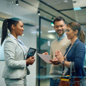 Young happy couple communicating with female real estate agent in office.